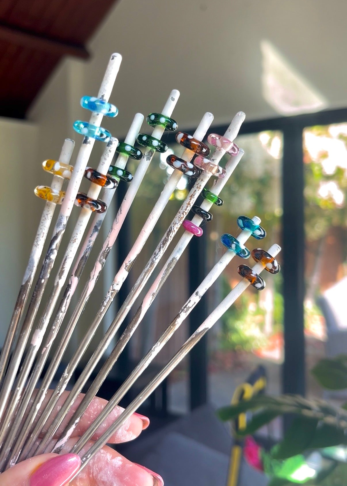 Set of colorful glass cocktail stirrers held by a hand with a blurred background