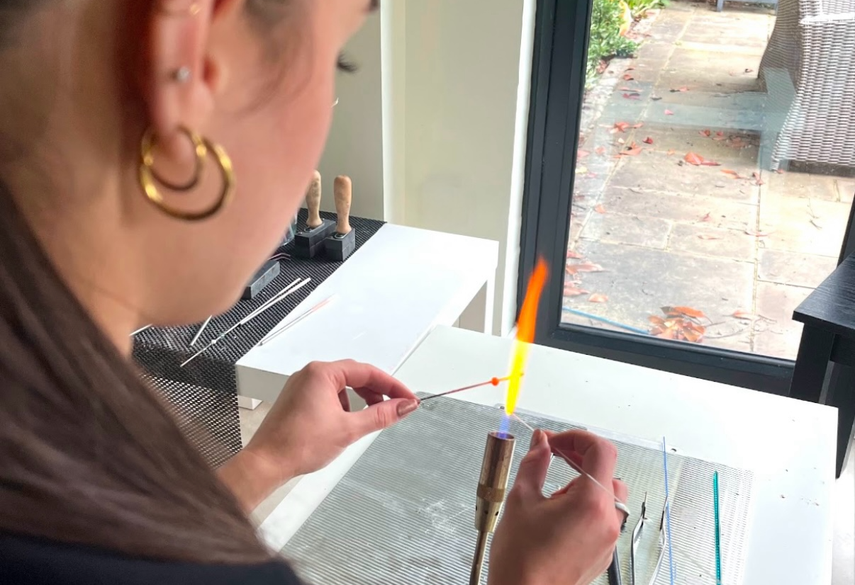 Person holding a small object near a window with outdoor view