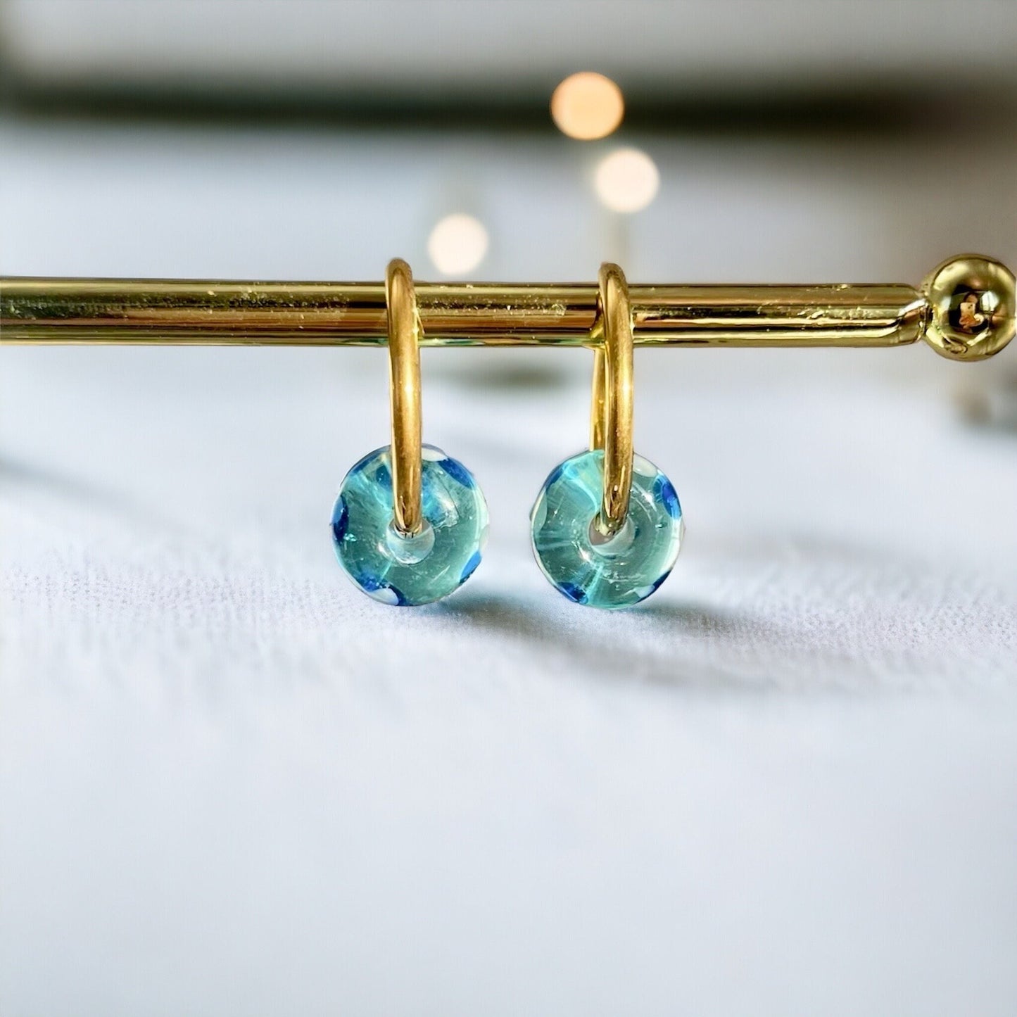 Gold hoop earrings with blue gemstones on a white background