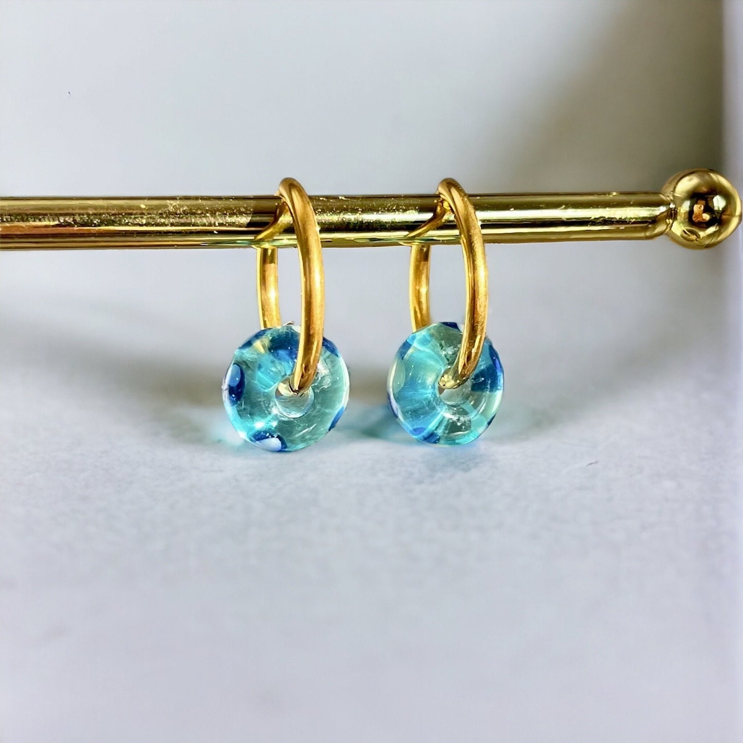 Gold hoop earrings with blue gemstones on a white background