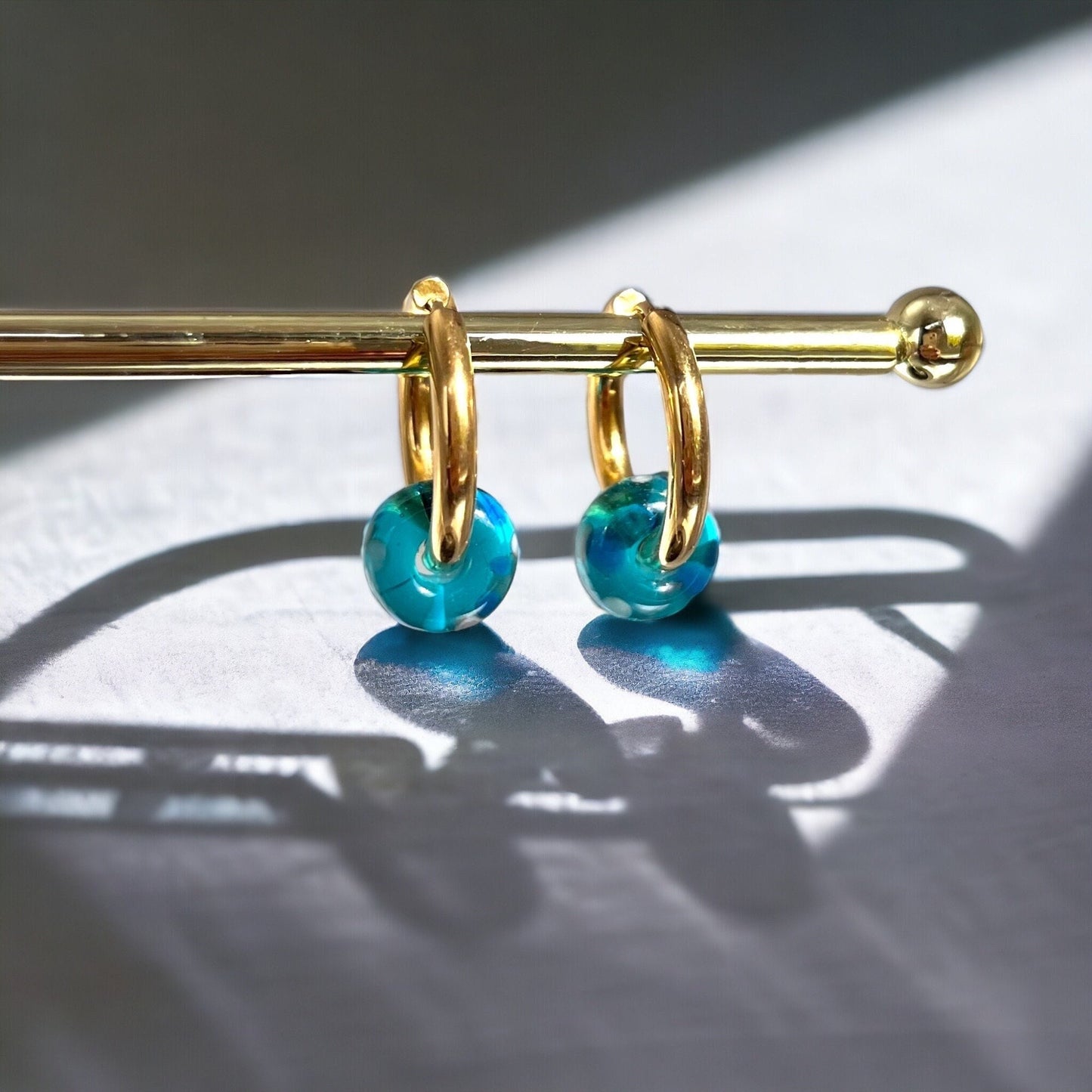 Gold hoop earrings with blue beads on a dark surface