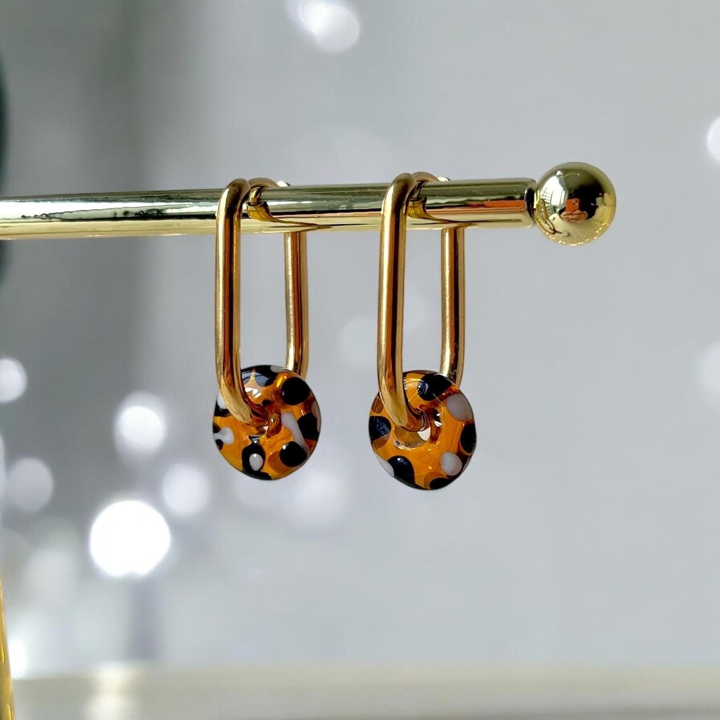 Gold earrings with tortoiseshell design on a blurred background