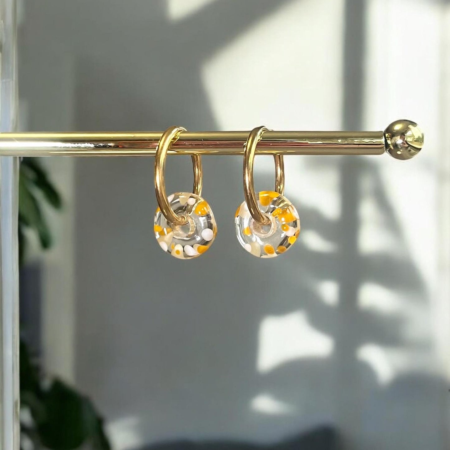 
                  
                    Gold shower curtain rings with decorative balls on a rod against a neutral background
                  
                