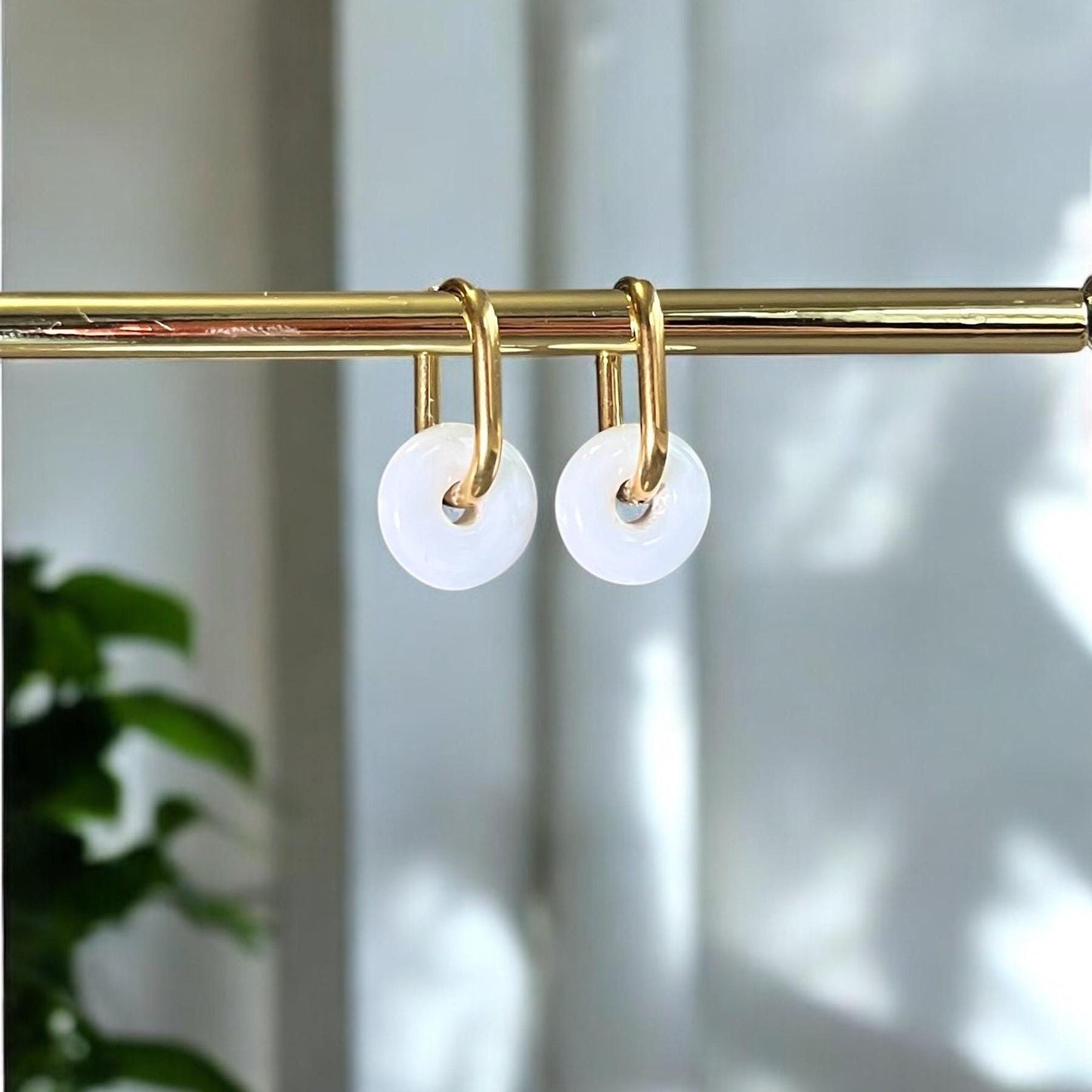 
                  
                    Gold shower curtain rod with white hooks against a neutral background
                  
                