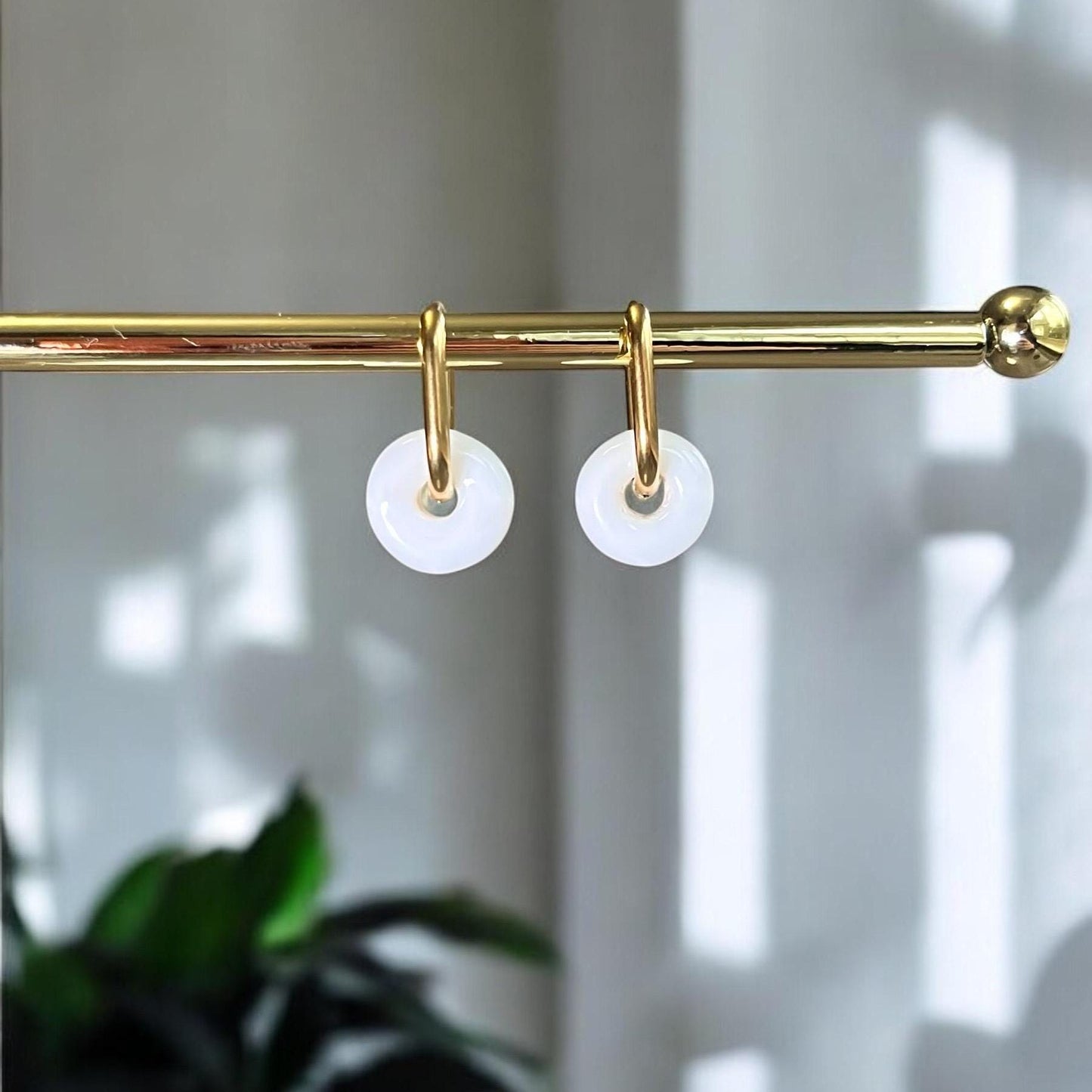 Gold curtain rod with white circular hooks on a neutral background