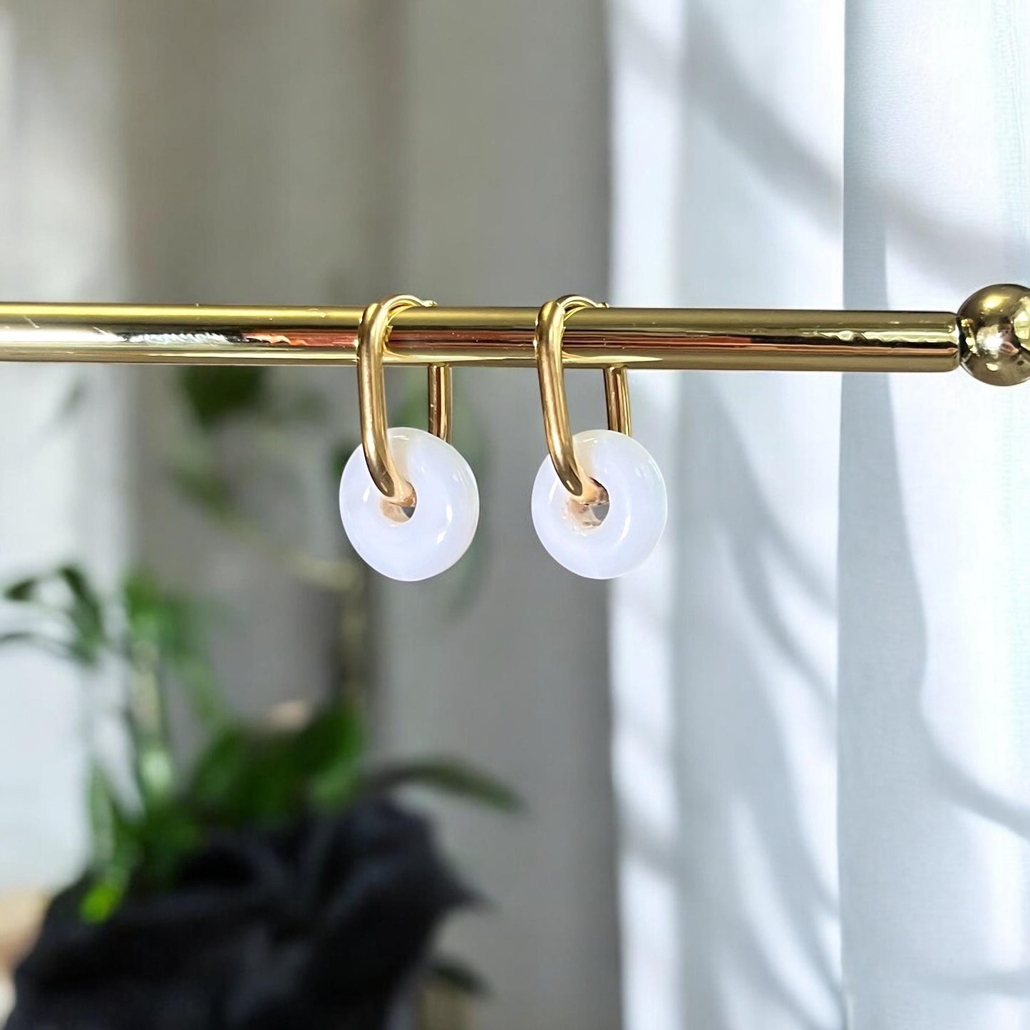
                  
                    Gold curtain rod with white shower hooks against a neutral background
                  
                