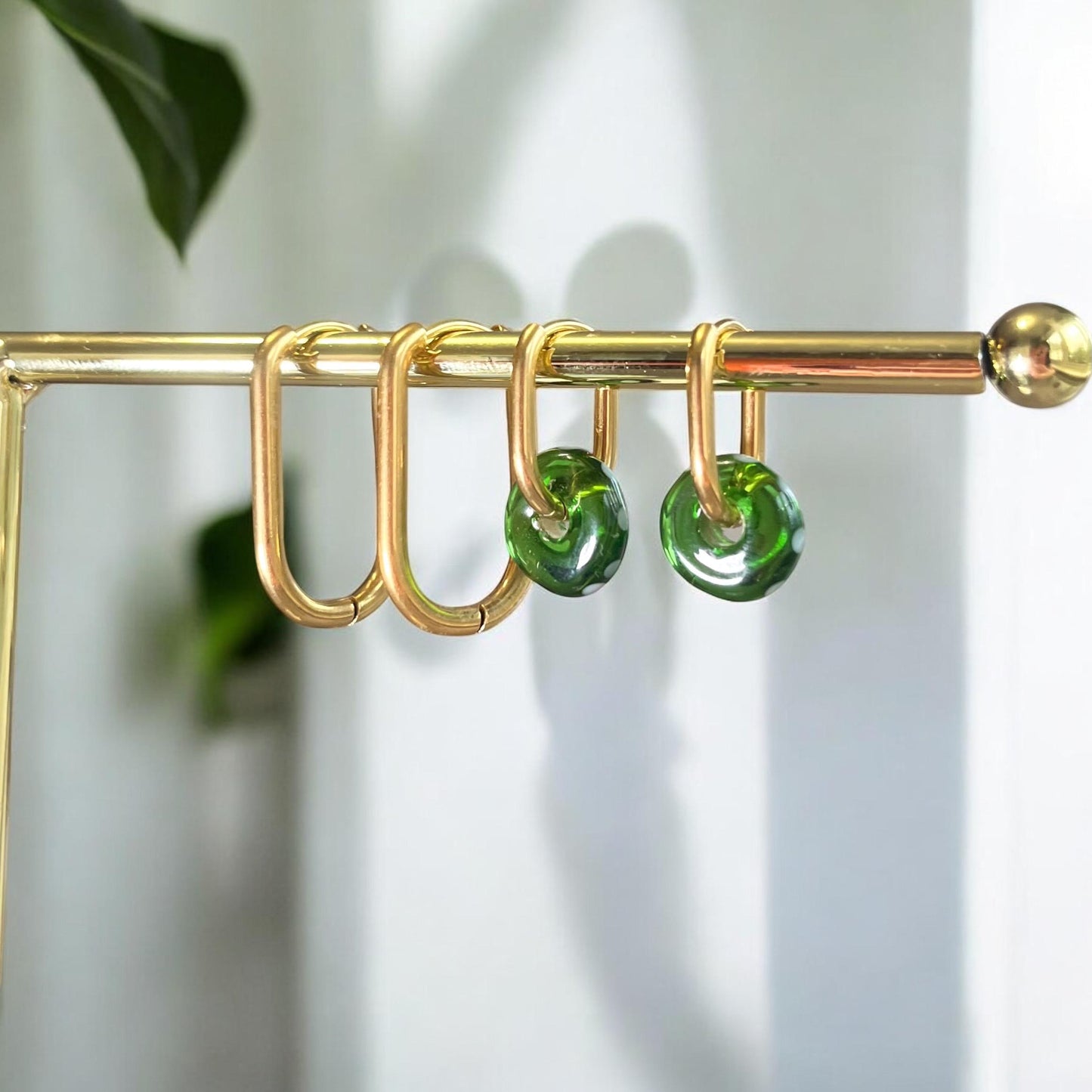 
                  
                    Gold curtain rod with green circular hooks against a white background
                  
                