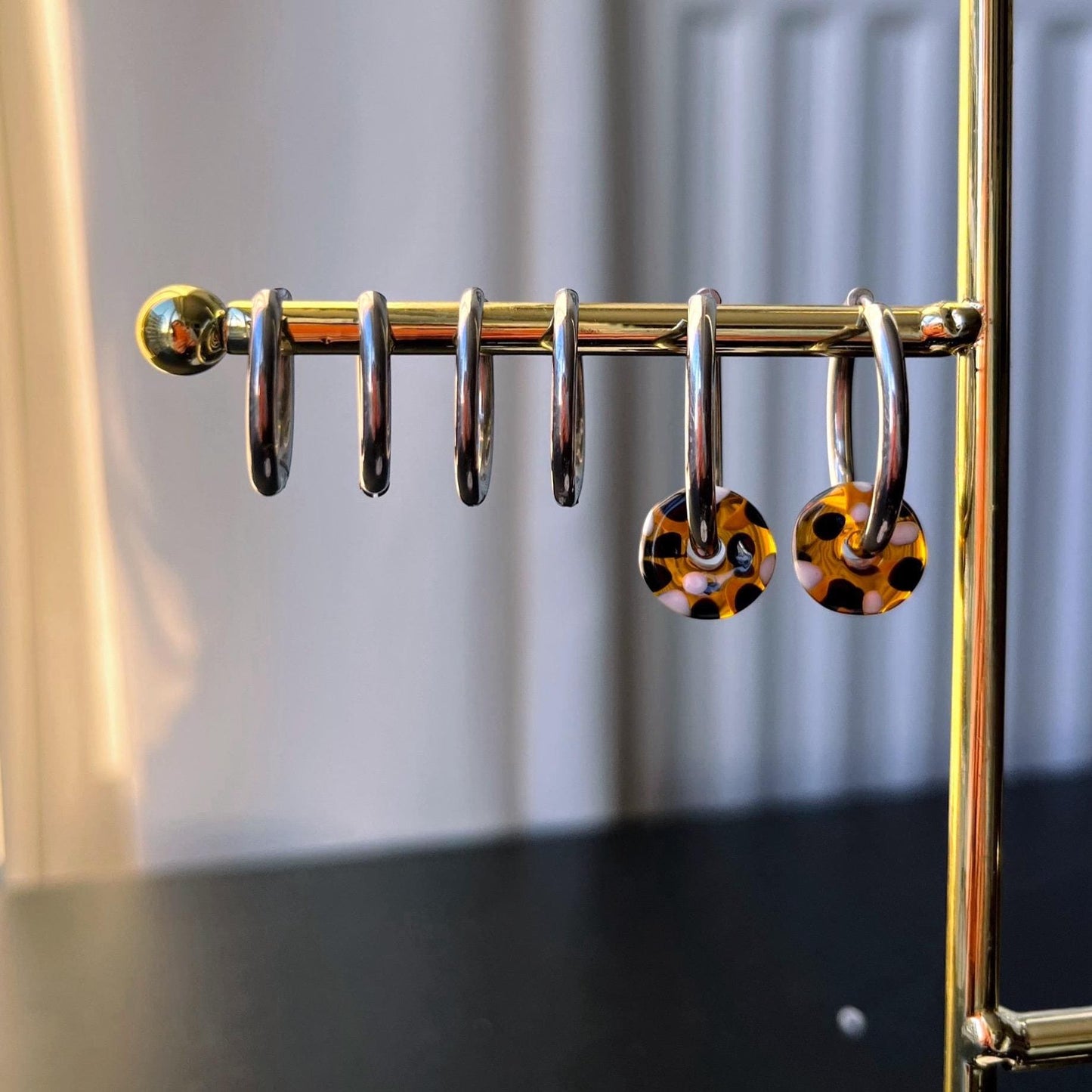 
                  
                    Pair of earrings with leopard print design on a gold stand against a neutral background
                  
                