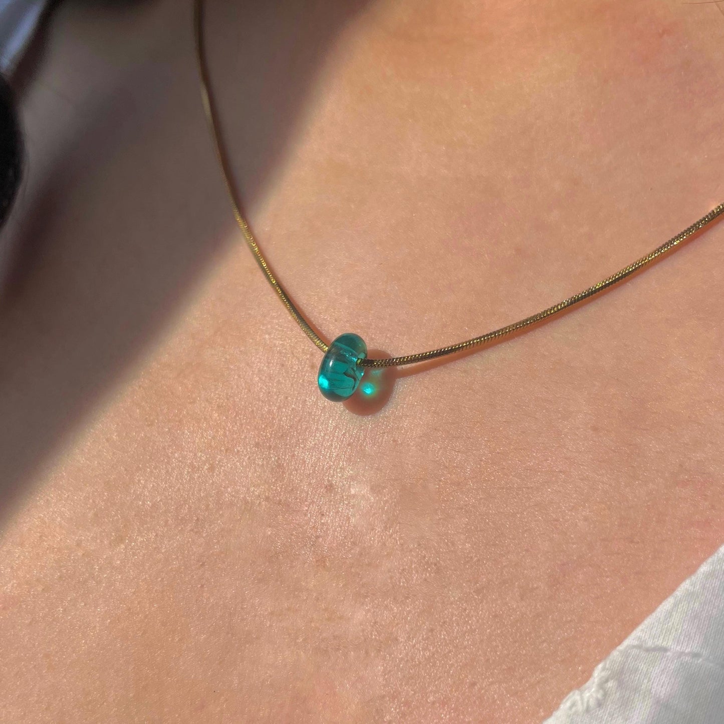 
                  
                    Necklace with a green heart-shaped pendant on a person's neck
                  
                