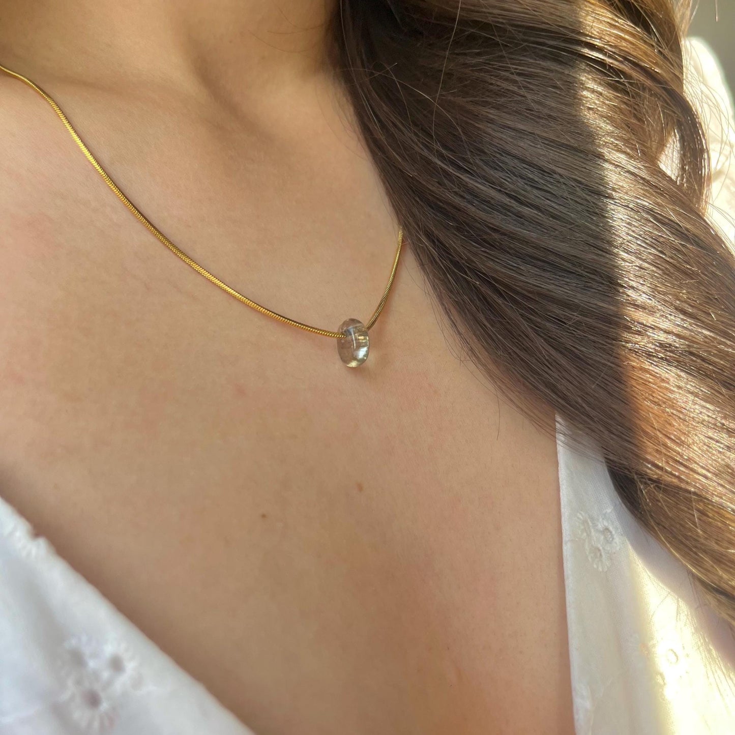 Gold necklace with a pendant worn by a person with long hair.