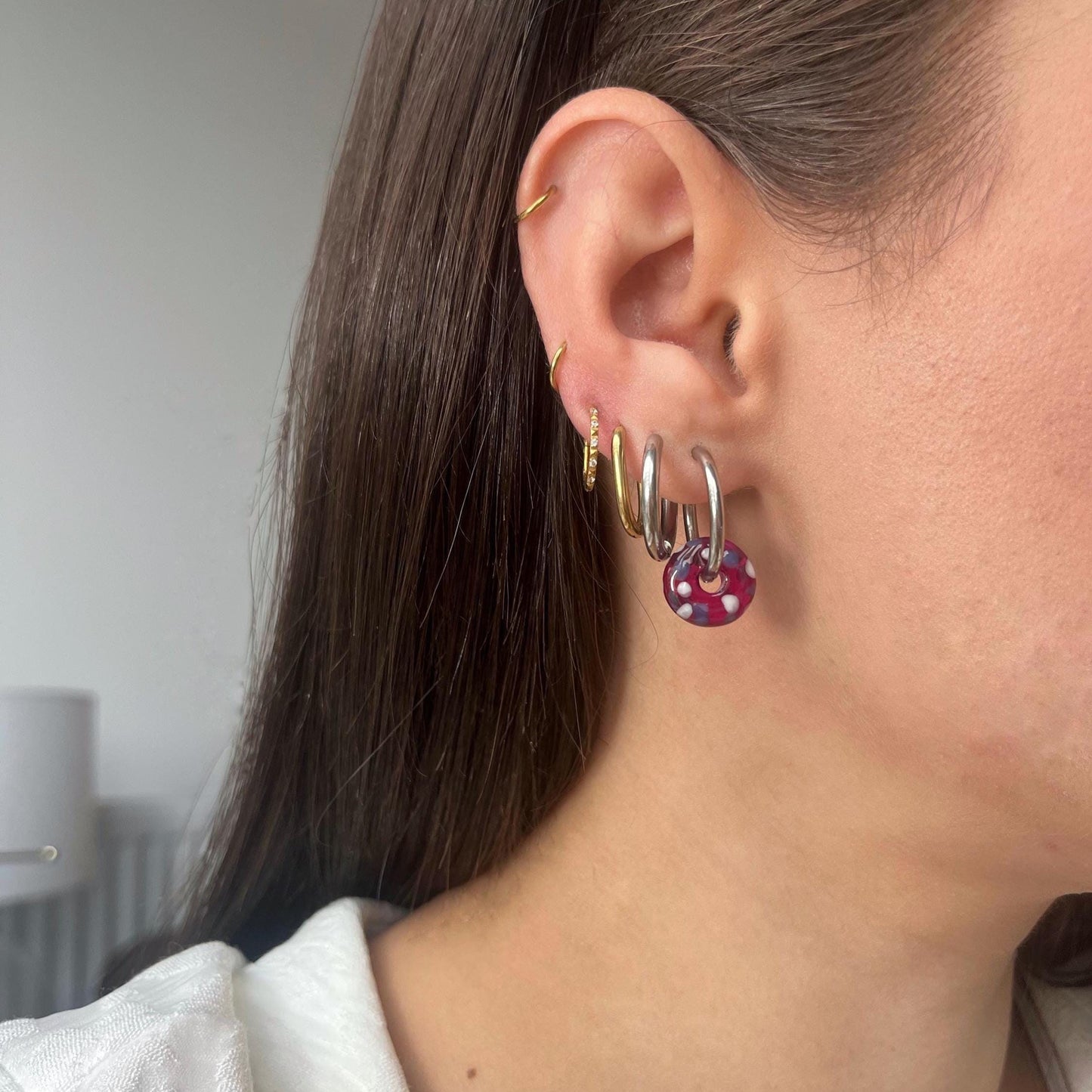 
                  
                    Close-up of an ear with multiple earrings against a neutral background
                  
                