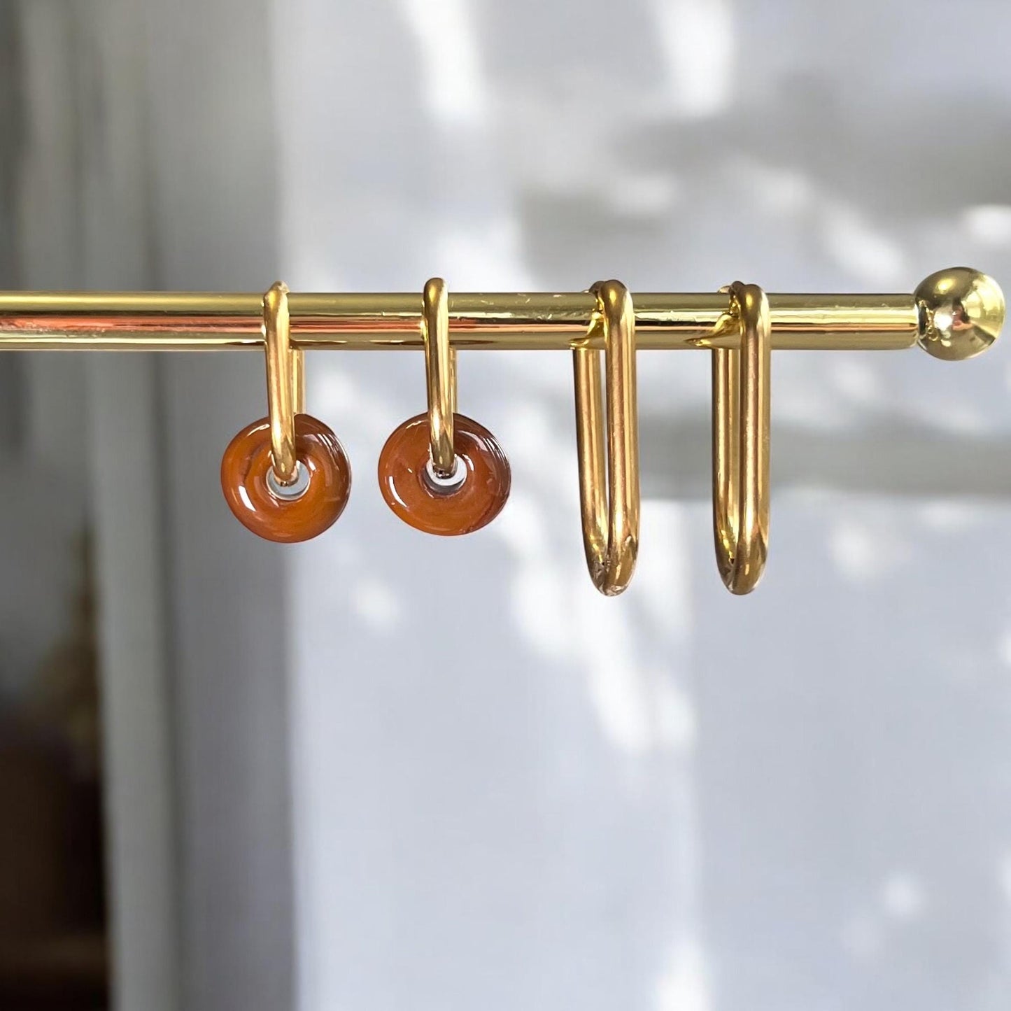 Gold curtain rod with orange curtain rings on a white background