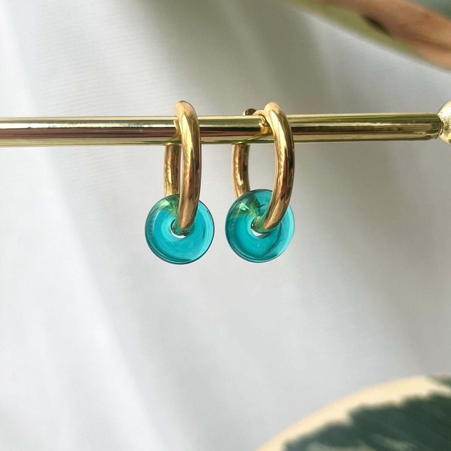 
                  
                    Gold hoop earrings with turquoise beads on a white background
                  
                