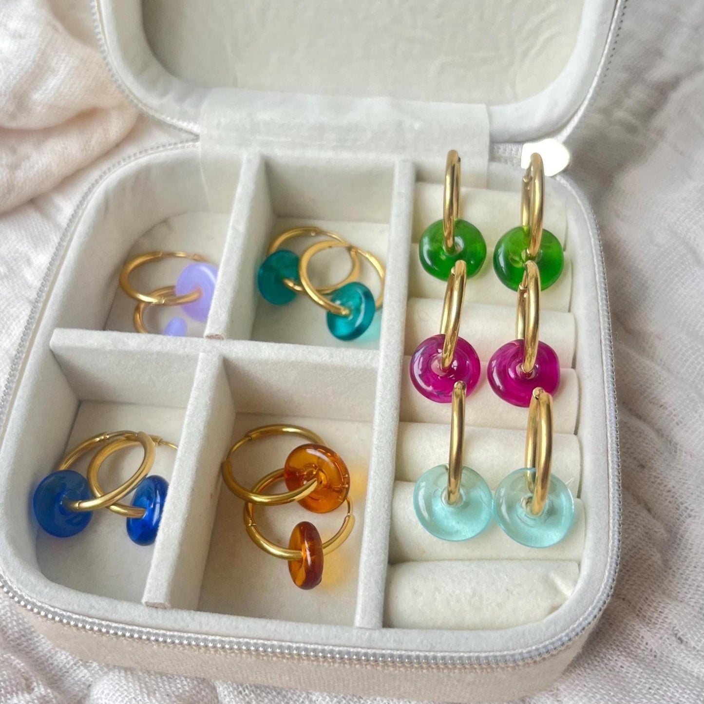 Colorful hoop earrings in a jewelry box with compartments.